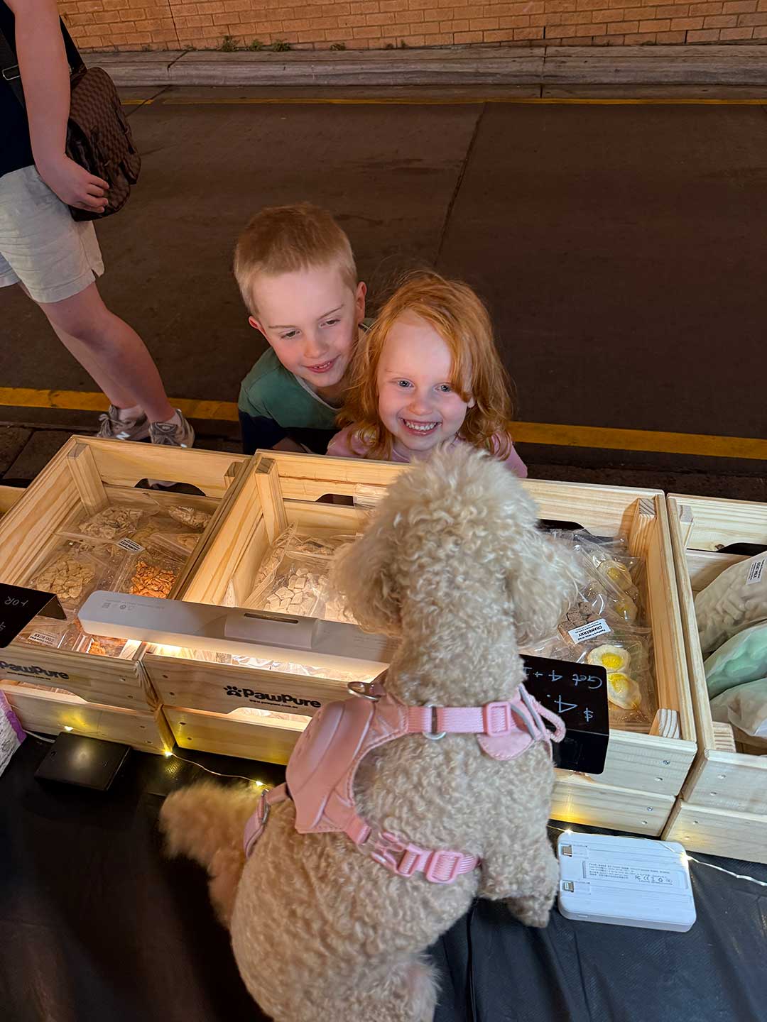 family and dog exploring pawpure freeze dried pet treats at local market stal